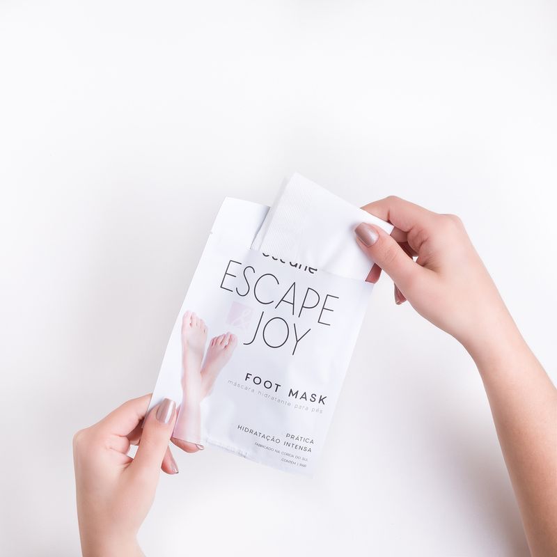 modelo-segurando-Mascara-Hidratante-Para-Pes-Com-Oleo-de-Coco-Foot-Mask-embalagem-fechada-frente